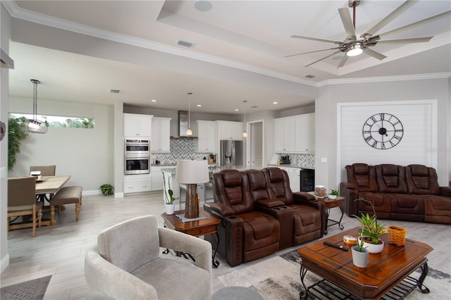 living area with a ceiling fan, light wood-style floors, a raised ceiling, recessed lighting, and ornamental molding