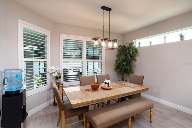dining space featuring light wood finished floors, baseboards, and a chandelier