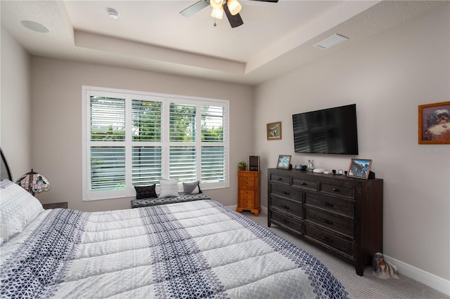 bedroom featuring carpet floors, baseboards, a raised ceiling, and ceiling fan