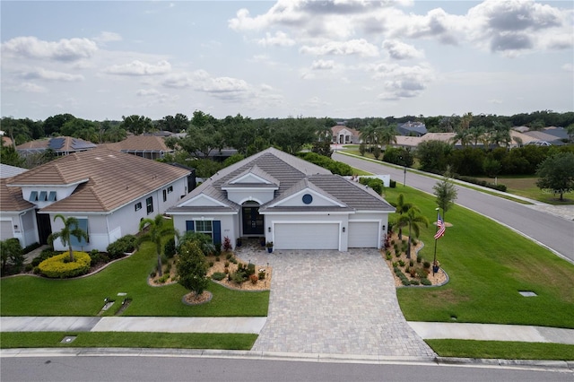 view of front of home featuring a garage, decorative driveway, a front lawn, and a residential view