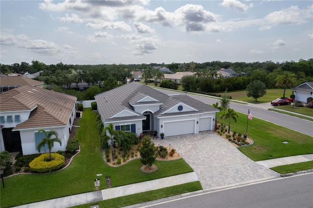 view of front of house with decorative driveway, a garage, a front yard, and stucco siding