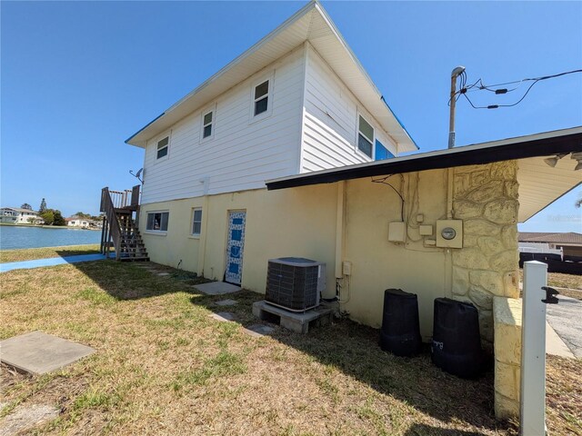 5930 Bahama Way N, St Pete Beach, FL 33706 - back of property with central air condition unit, a lawn, stairway, a water view, and stucco siding