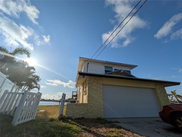 5930 Bahama Way N, St Pete Beach, FL 33706 - view of side of home with stone siding, a water view, and a garage