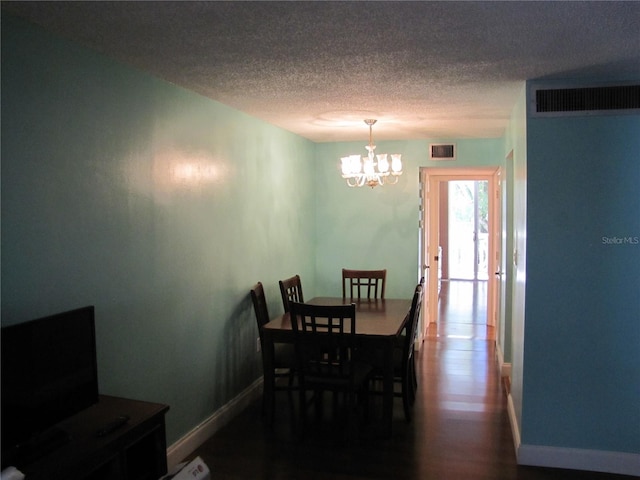 dining area featuring a textured ceiling, a chandelier, baseboards, and dark wood finished floors