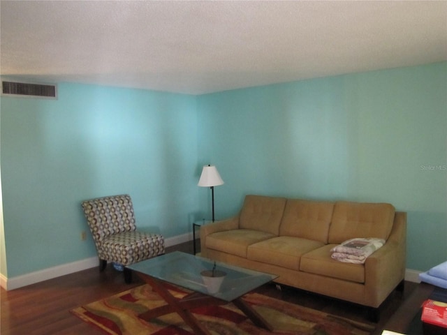 living room featuring wood finished floors, baseboards, and a textured ceiling
