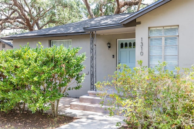 1310 Hilton Pl, Tampa, FL 33604 - view of exterior entry featuring stucco siding and a shingled roof
