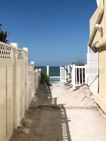 view of yard with a water view, fence, and a view of the beach