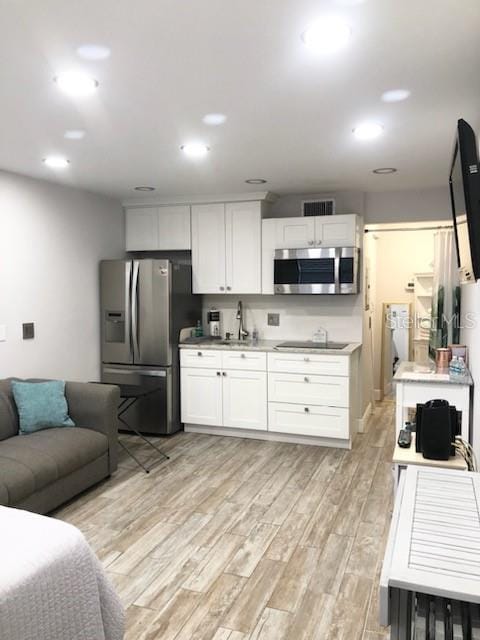 kitchen with appliances with stainless steel finishes, visible vents, light wood-style flooring, and white cabinetry