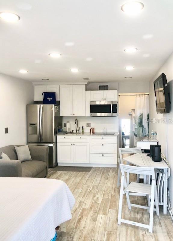 kitchen featuring light wood finished floors, visible vents, a sink, stainless steel appliances, and white cabinets
