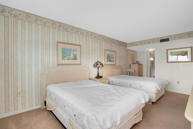 carpeted bedroom with connected bathroom, baseboards, visible vents, and wallpapered walls
