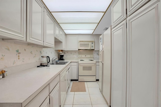 kitchen featuring light tile patterned floors, a sink, white appliances, backsplash, and light countertops