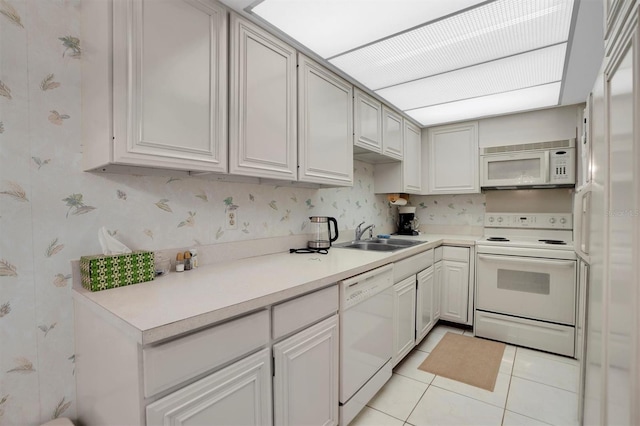 kitchen with wallpapered walls, light tile patterned floors, white appliances, a sink, and light countertops