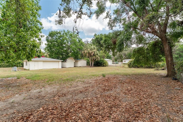 view of grassy yard featuring a detached garage and view of wooded area