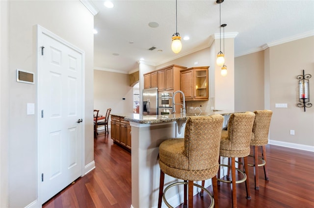 3300 Stonegate Falls Dr, Land O Lakes, FL 34638 - kitchen featuring appliances with stainless steel finishes, dark wood-type flooring, crown molding, a kitchen bar, and light stone counters