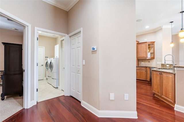 3300 Stonegate Falls Dr, Land O Lakes, FL 34638 - hallway featuring a sink, washing machine and clothes dryer, ornamental molding, dark wood-style floors, and baseboards
