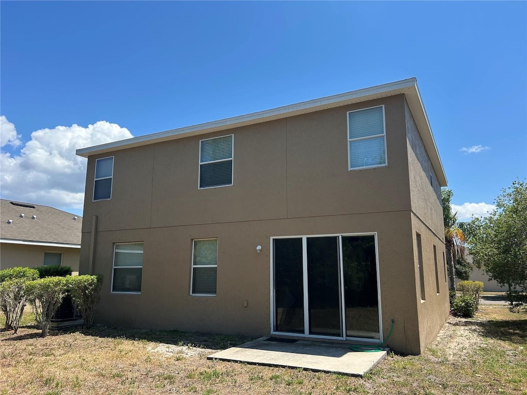 rear view of house featuring stucco siding