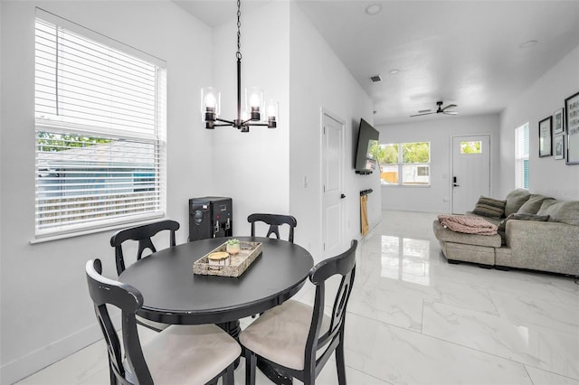 dining room featuring a chandelier, light marble finish floors, ceiling fan, and baseboards