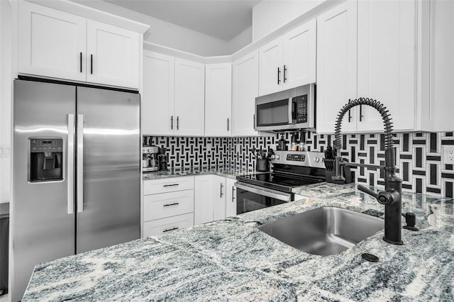 kitchen featuring appliances with stainless steel finishes, a sink, light stone counters, and backsplash