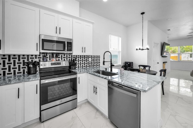 kitchen featuring stainless steel appliances, a sink, a peninsula, and light marble finish flooring