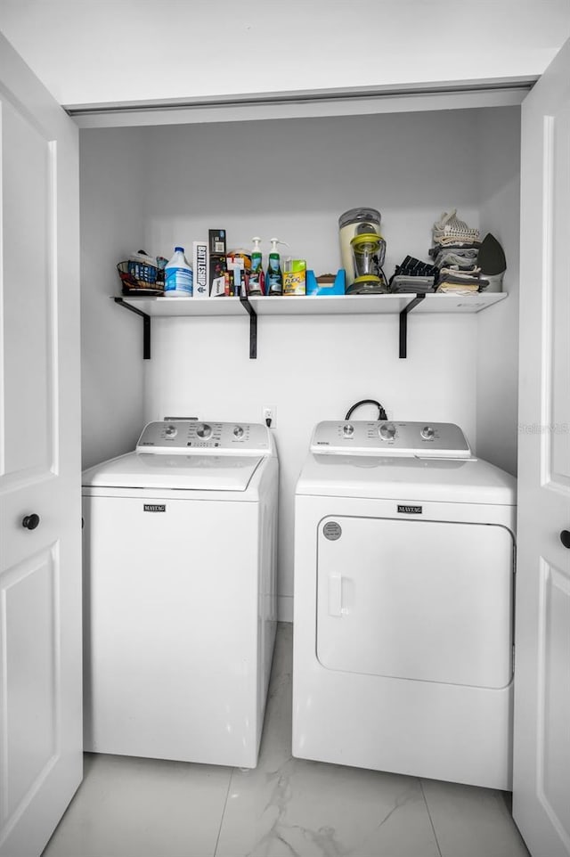 laundry area featuring washer and clothes dryer and light marble finish flooring
