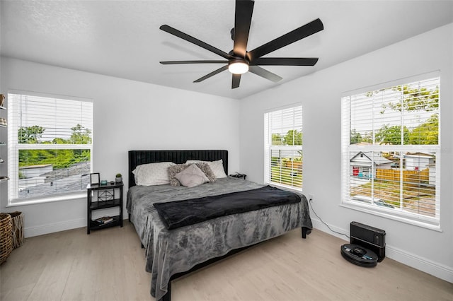 bedroom with light wood-type flooring, baseboards, and ceiling fan
