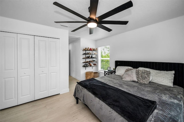bedroom with light wood-style floors, ceiling fan, a closet, and baseboards