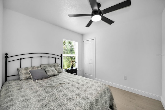 bedroom with wood finished floors, baseboards, a closet, and a ceiling fan
