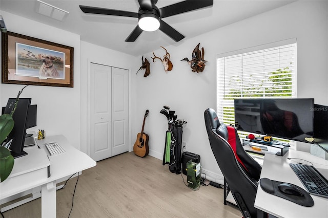 home office with light wood-style floors, a ceiling fan, and baseboards