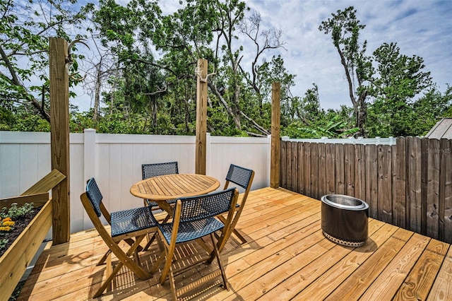 wooden deck featuring outdoor dining space and view of wooded area