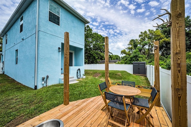 wooden terrace with a storage shed, outdoor dining space, and an outdoor structure