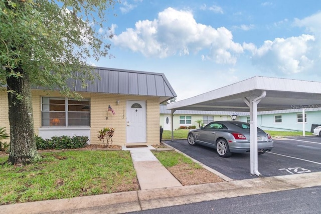 11723 Boynton Ln Unit 1, New Port Richey, FL 34654 - view of front facade with brick siding, covered parking, and metal roof