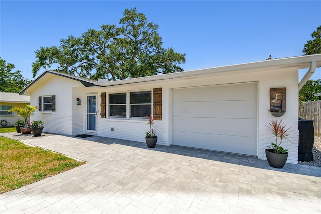 single story home featuring an attached garage, brick siding, and decorative driveway