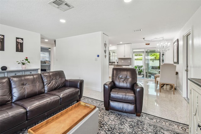 living area with a chandelier, baseboards, speckled floor, recessed lighting, and a textured ceiling