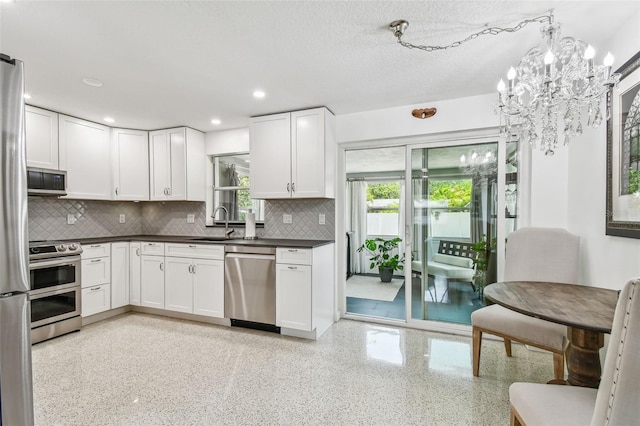 kitchen featuring stainless steel appliances, dark countertops, tasteful backsplash, a chandelier, and recessed lighting