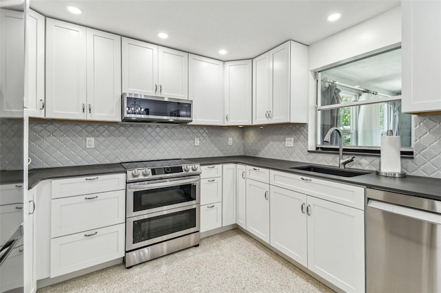 kitchen with appliances with stainless steel finishes, a sink, dark countertops, and recessed lighting
