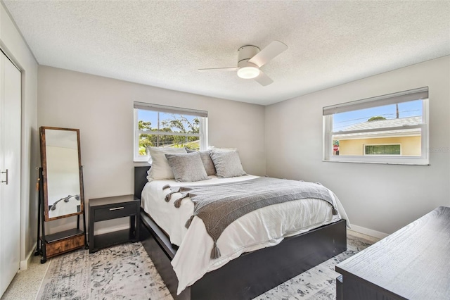 bedroom featuring baseboards, a ceiling fan, and a textured ceiling