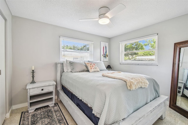 bedroom with baseboards, speckle patterned floor, ceiling fan, and a textured ceiling