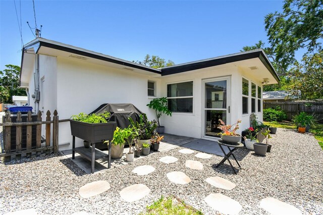 back of property with fence, stucco siding, and a patio