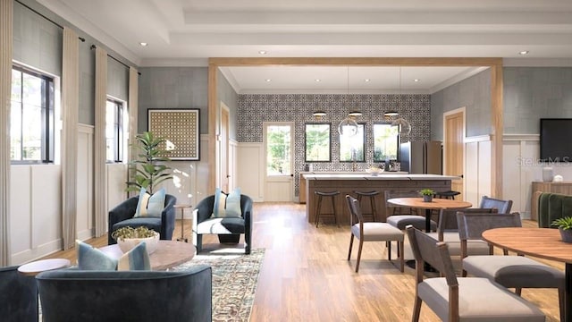 living room with light wood finished floors, plenty of natural light, a decorative wall, and ornamental molding
