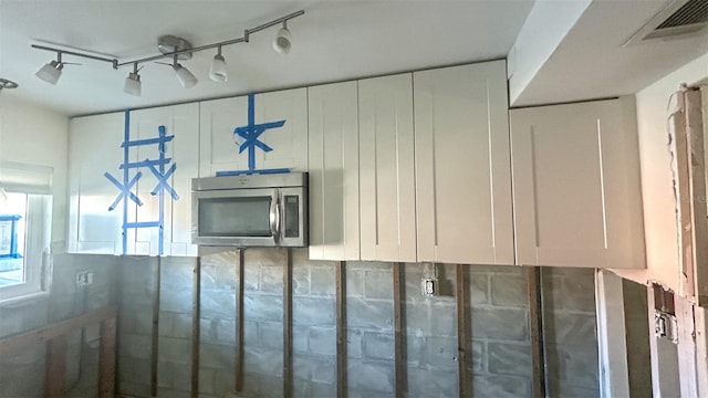 interior space with stainless steel microwave, rail lighting, and visible vents