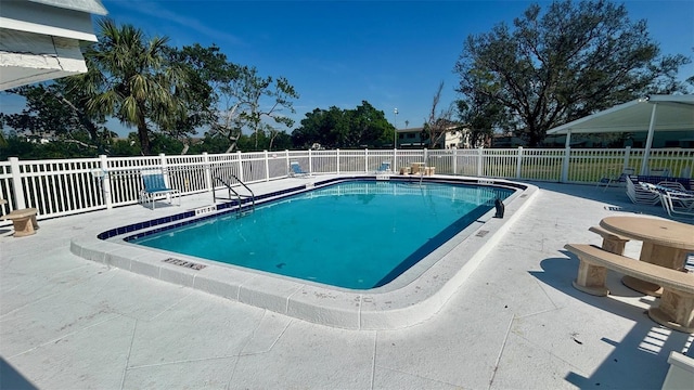 community pool with a patio and fence