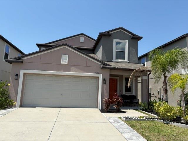 traditional-style home featuring concrete driveway, an attached garage, and stucco siding