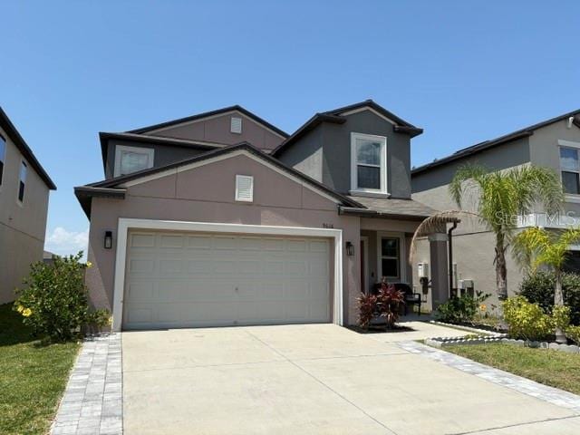 traditional-style house featuring concrete driveway and stucco siding