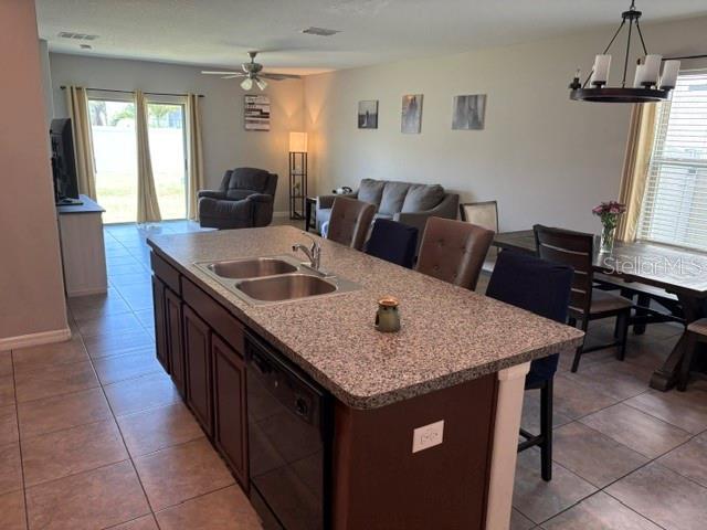 kitchen featuring open floor plan, ceiling fan with notable chandelier, a sink, and dishwasher