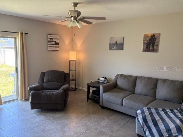 living area with light tile patterned floors and a ceiling fan