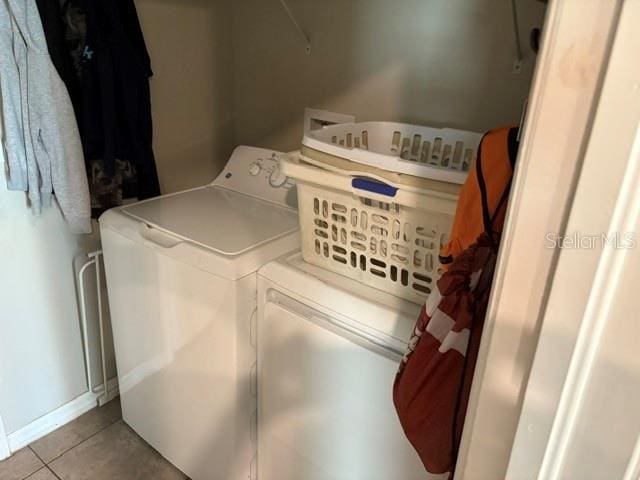 clothes washing area with separate washer and dryer, laundry area, tile patterned floors, and baseboards