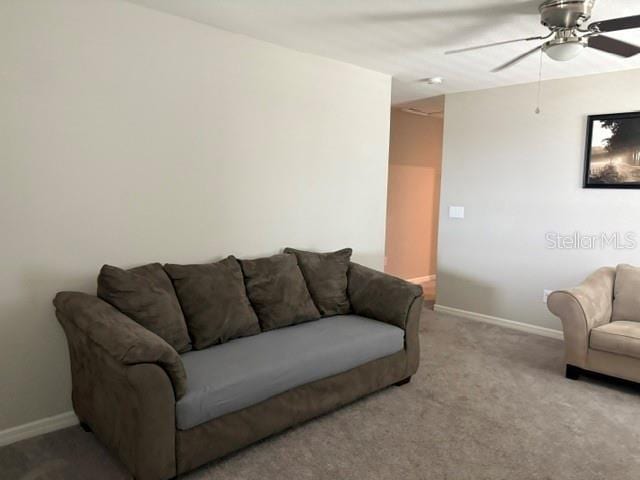 living room featuring carpet flooring, baseboards, and a ceiling fan