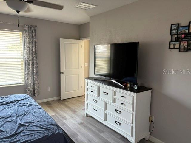 bedroom featuring light wood-style flooring, baseboards, a ceiling fan, and visible vents