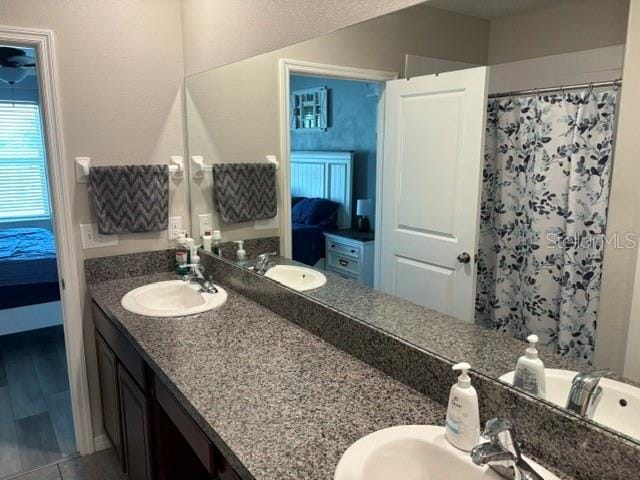 bathroom featuring double vanity, connected bathroom, and a sink