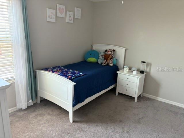 bedroom featuring light colored carpet and baseboards